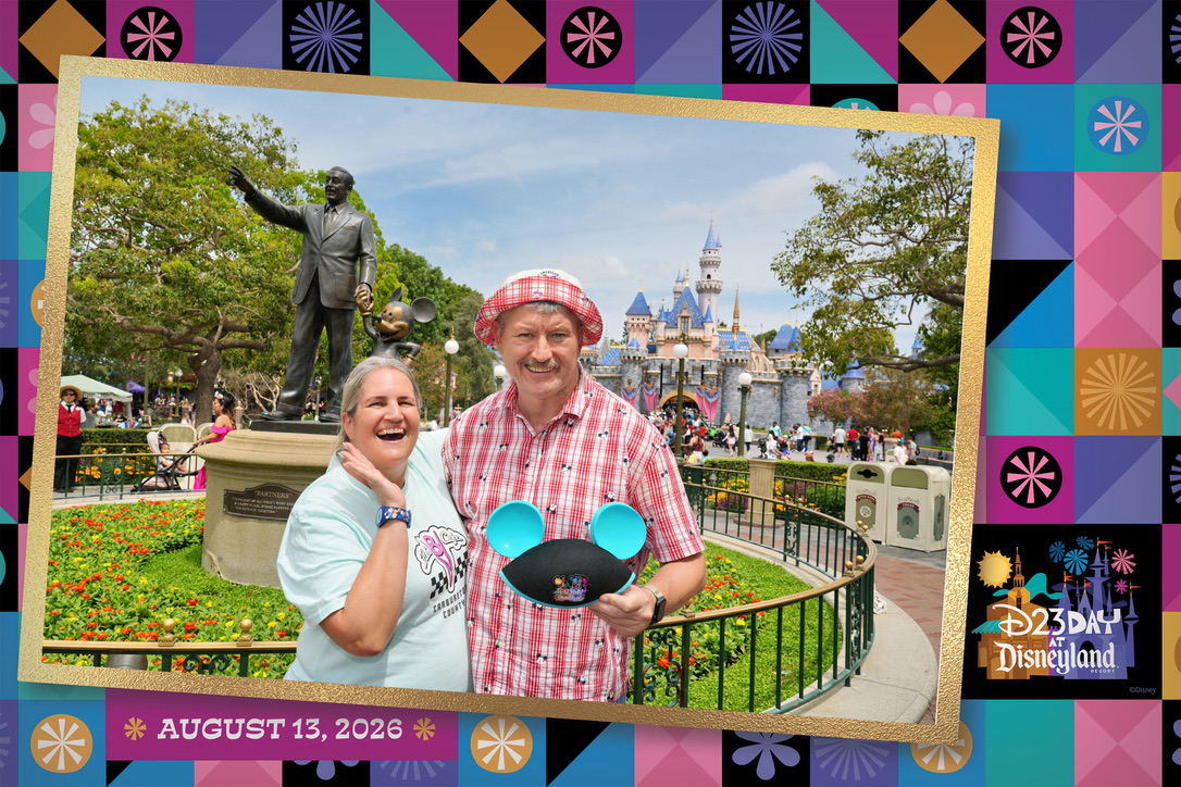 Stefanie und André vor der Partners-Statue und dem Disneyland-Schloss beim D23 Day 2026, mit buntem Rahmen