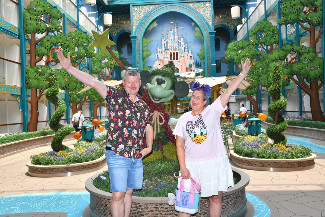 Unser Disney-Reisepärchen vor einer Mickey-Figur an Bord eines Disney-Schiffs